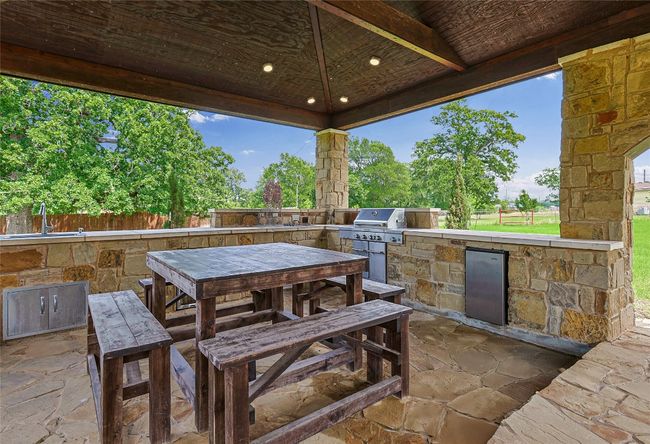 View of patio with exterior kitchen, a sink, a gazebo, fence, and a grill | Image 26