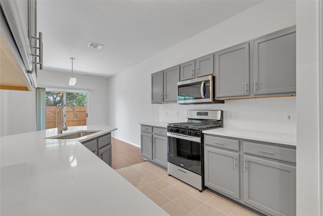 Kitchen with stainless steel appliances, gray cabinets, and light countertops | Image 10