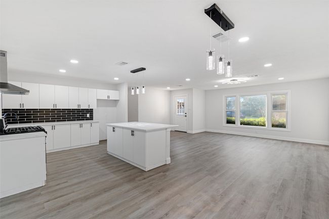 Kitchen featuring light wood-type flooring, white cabinets, decorative light fixtures, and a center island | Image 8
