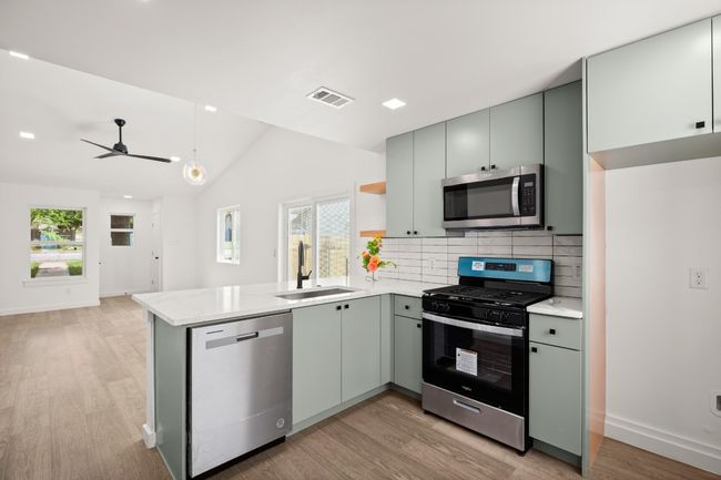 Kitchen with stainless steel appliances, a peninsula, light wood-style flooring, backsplash, and vaulted ceiling | Image 24