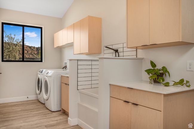 Laundry area with independent washer and dryer, light wood-style floors, baseboards, and cabinet space | Image 38