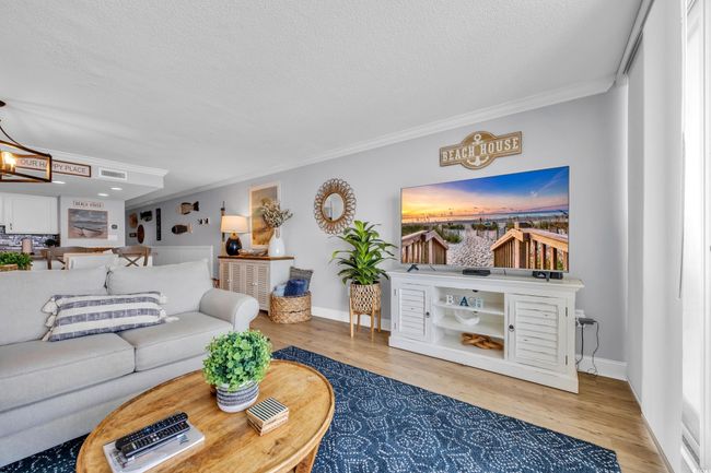 Living area featuring a textured ceiling, ornamental molding, wood finished floors, a chandelier, and baseboards | Image 12