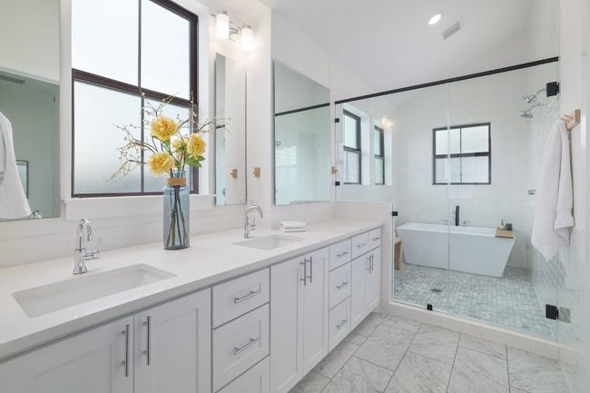 Luxurious primary bathroom with marble finish floors, double vanity, a bathing pod with soaking tub, and dual shower heads | Image 15