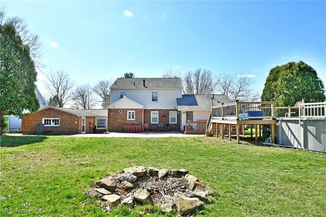 Rear view of house with brick siding, a wooden deck, a yard, and a patio area | Image 6