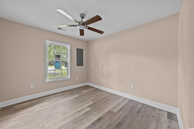 Empty room with wood finished floors, ceiling fan, and electric panel | Image 30