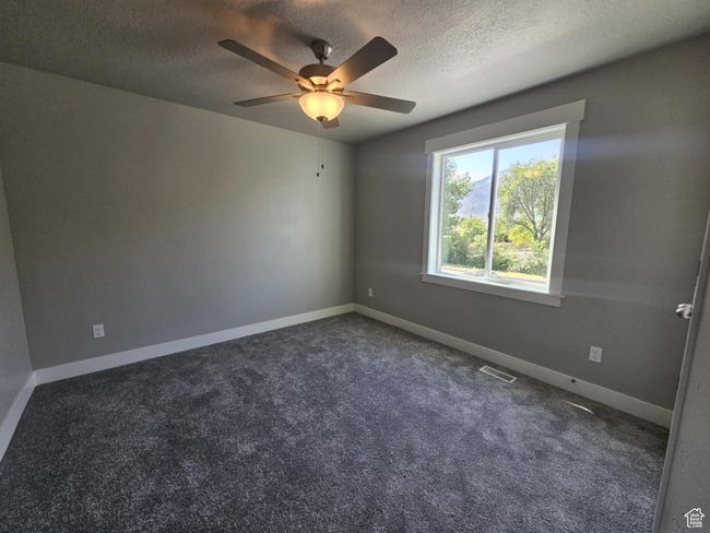 Carpeted spare room with a textured ceiling, ceiling fan, and baseboards | Image 8
