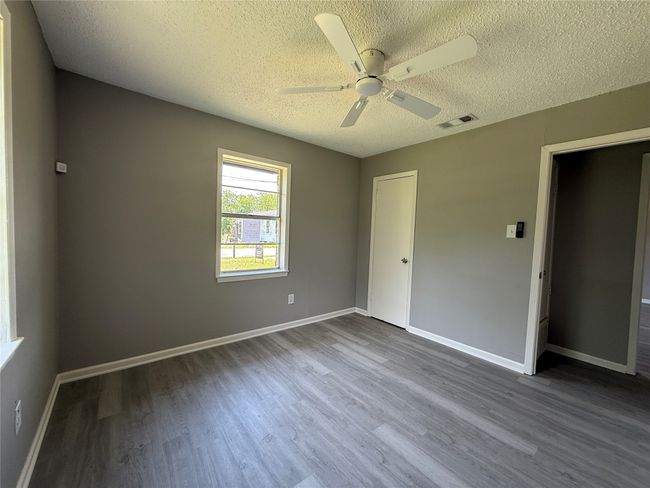 Unfurnished bedroom featuring a textured ceiling, wood finished floors, baseboards, and ceiling fan. View 2 | Image 9