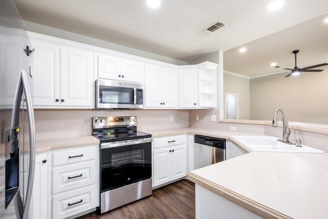 Kitchen with stainless steel appliances, recessed lighting, dark wood finished floors, white cabinetry, and ceiling fan | Image 24