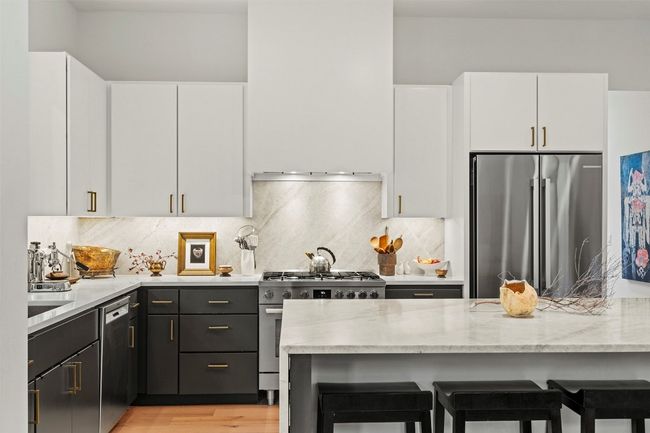 Kitchen featuring appliances with stainless steel finishes, white cabinets, a breakfast bar area, and tasteful backsplash | Image 16