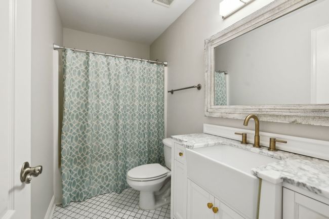 Second full bathroom upstairs with a marble-topped vanity and brass fixtures. | Image 31