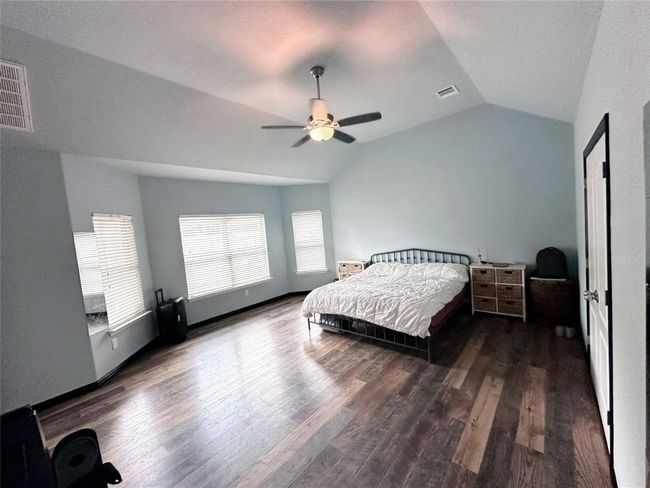 Very large primary first floor bedroom featuring lofted ceiling, wood finished floors, and ceiling fan | Image 17