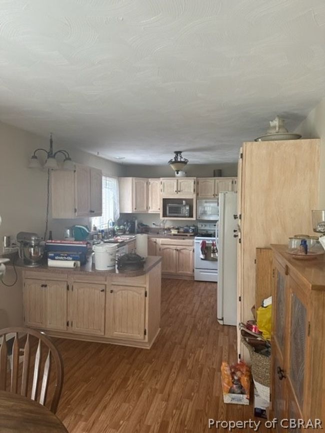 Kitchen with fridge, range, light brown cabinetry, and dark wood-type flooring | Image 11