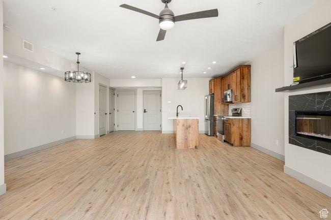 Unfurnished living room featuring light wood finished floors, ceiling fan, baseboards, a fireplace, and recessed lighting | Image 12