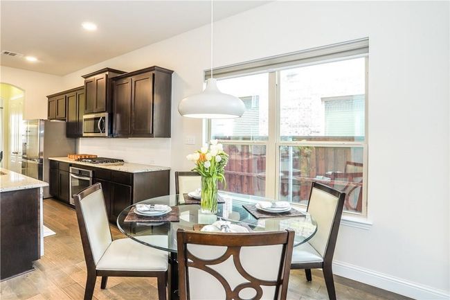 Kitchen featuring appliances with stainless steel finishes, dark brown cabinets, arched walkways, light wood finished floors, and recessed lighting | Image 11