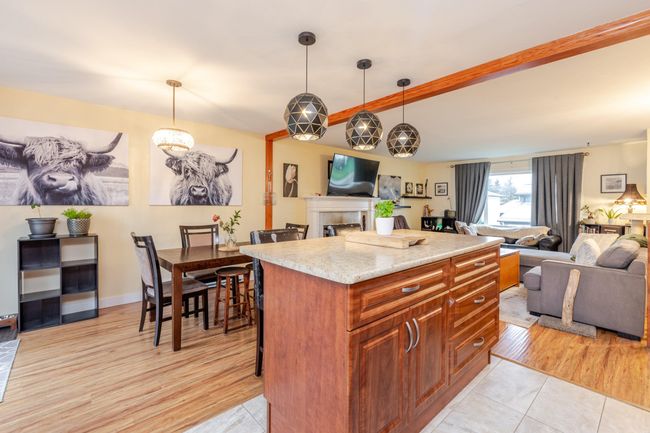 Kitchen featuring open floor plan, hanging light fixtures, beam ceiling, a center island, and brown cabinets | Image 10