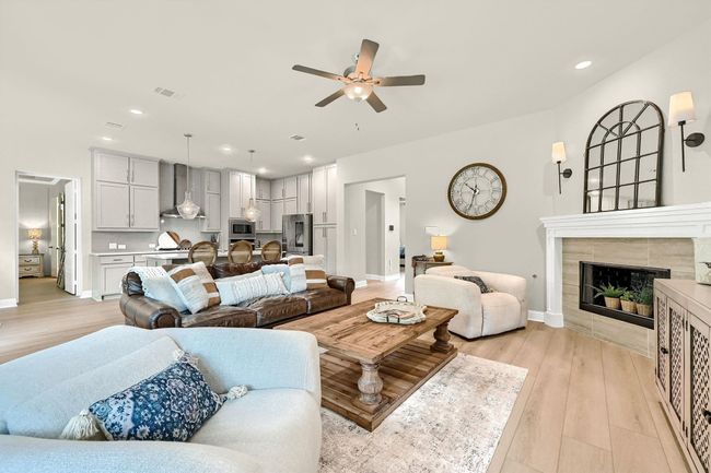 Living area featuring a ceiling fan, recessed lighting, baseboards, a tiled fireplace, and light wood-type flooring | Image 10
