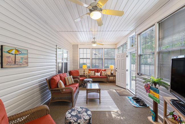 Sunroom with an outdoor hangout area, ceiling fan, carpet, and wood walls | Image 34