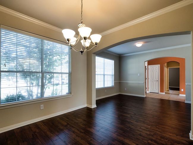 Unfurnished room with arched walkways, a chandelier, hardwood / wood-style flooring, baseboards, and crown molding | Image 15