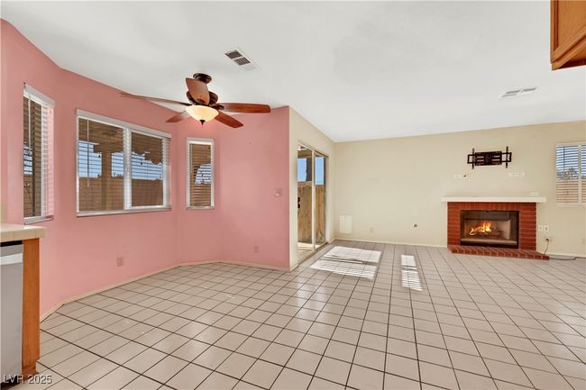 Unfurnished living room with a brick fireplace, visible vents, ceiling fan, and light tile patterned floors | Image 14