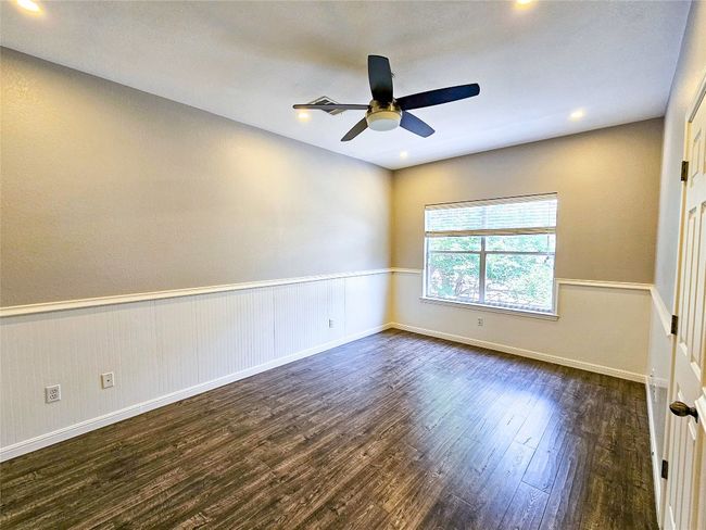 Empty room with dark wood-style floors, a ceiling fan, recessed lighting, wainscoting, and baseboards | Image 19