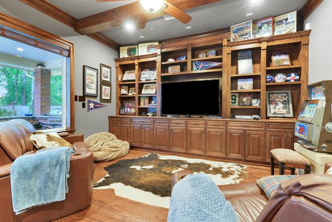 Rich wood accents set the tone, from the coffered ceiling with exposed wood beams to the handsome hardwood flooring underfoot. A wall of custom built-in shelving is thoughtfully designed to accommodate your media and entertainment needs, and the space is wired for surround sound, creating an cinematic experience. | Image 19