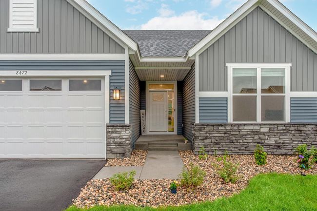 Clean lines and manicured landscaping enhance the home's inviting front façade, complemented by a covered entry and striking stonework. | Image 43