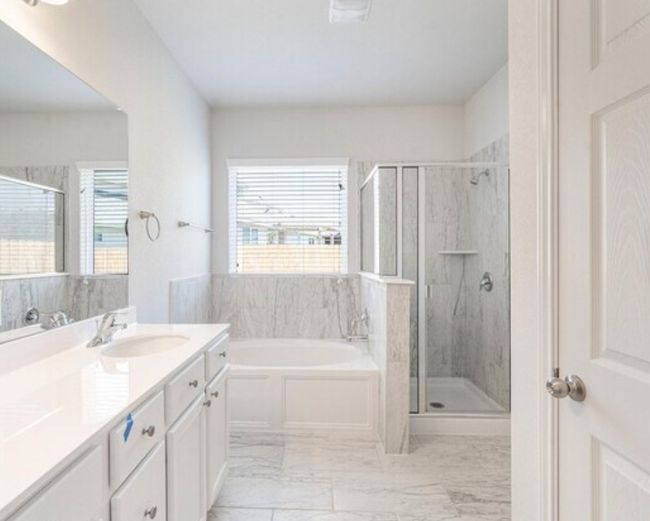 Full bath featuring a garden tub, a stall shower, vanity, and healthy amount of natural light | Image 11