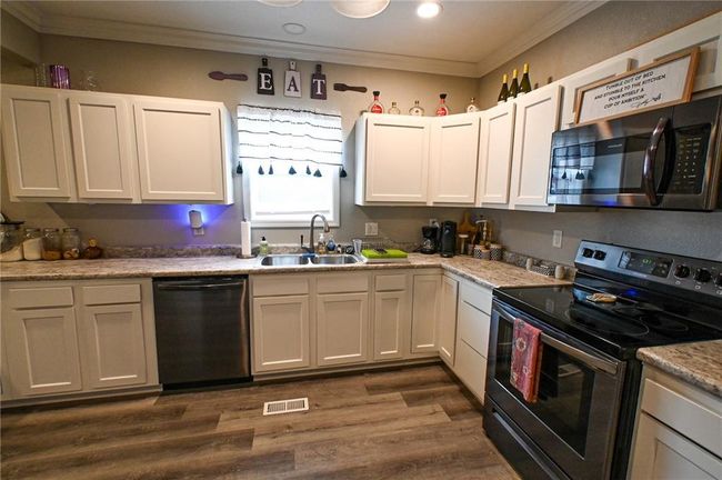 Kitchen featuring electric stove, dishwashing machine, a sink, ornamental molding, and dark wood-style floors | Image 13
