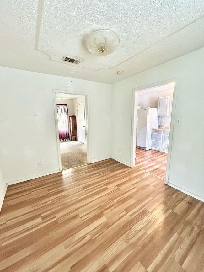 Unfurnished room featuring light wood finished floors, a textured ceiling, and baseboards | Image 9
