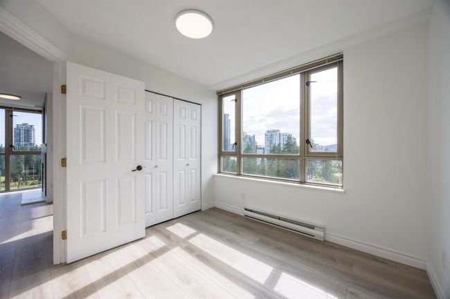 Unfurnished bedroom with a baseboard heating unit, multiple windows, a city view, and light wood-style floors | Image 5