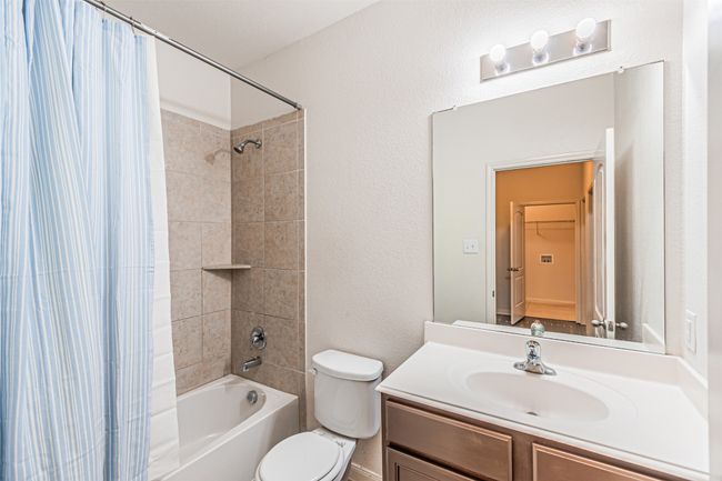 Full bath featuring shower / bath combo, vanity, toilet, and a textured wall | Image 22
