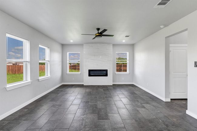 Unfurnished living room featuring ceiling fan, a premium fireplace, baseboards, and recessed lighting | Image 9