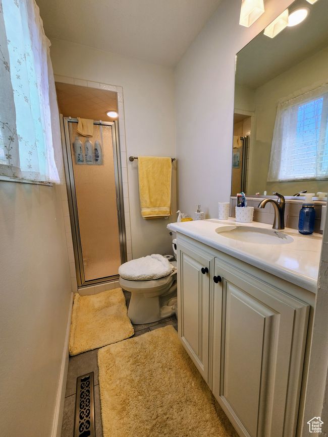 Bathroom featuring tile patterned flooring, a stall shower, vanity, baseboards, and toilet | Image 27