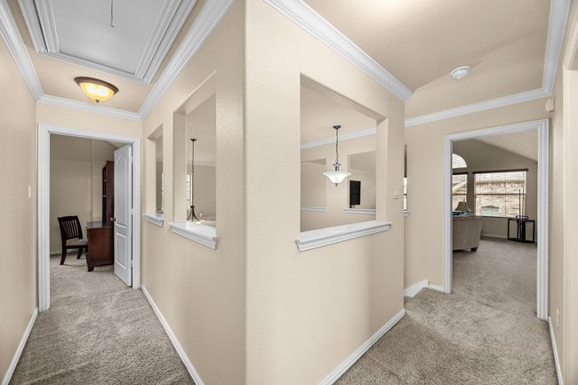 The hallway leading around the bedrooms upstairs with open cutouts to allow light throughout the home. | Image 31