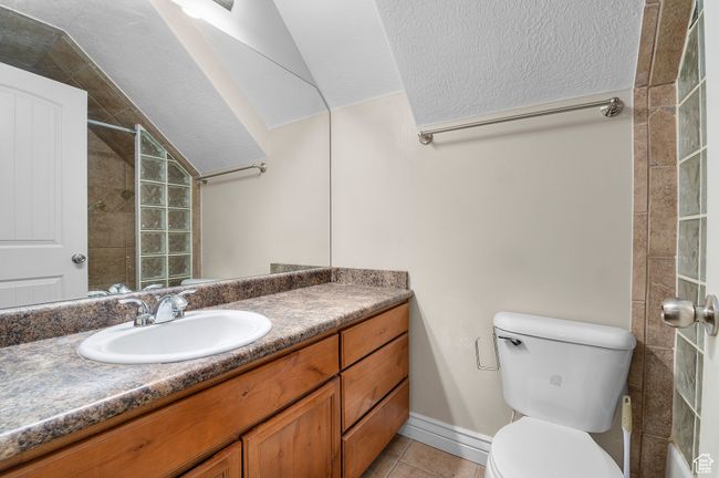 Bathroom featuring vanity, tile patterned floors, toilet, baseboards, and lofted ceiling | Image 19