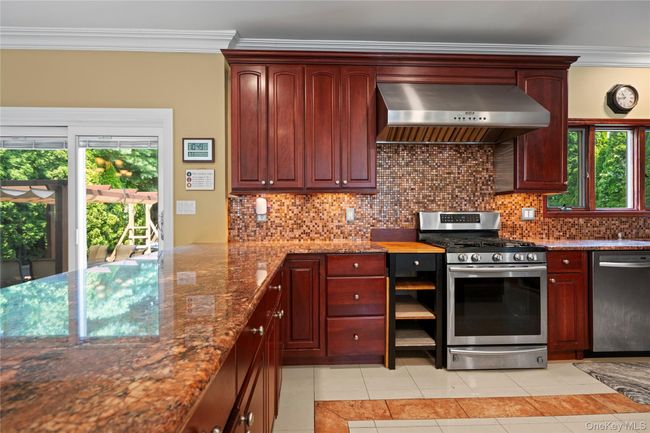 Kitchen featuring ornamental molding, stainless steel appliances, exhaust hood, light tile patterned floors, and tasteful backsplash | Image 10