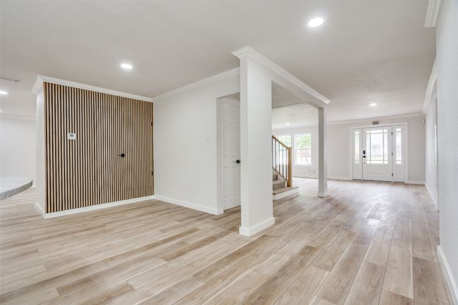 Unfurnished living room featuring crown molding, stairway, light wood-style floors, and recessed lighting | Image 13