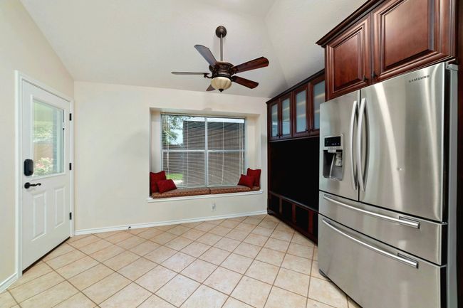 Start your day in style with a charming breakfast area featuring inviting window seating, custom cabinetry, and a sleek stainless steel fridge—where comfort meets craftsmanship. | Image 12