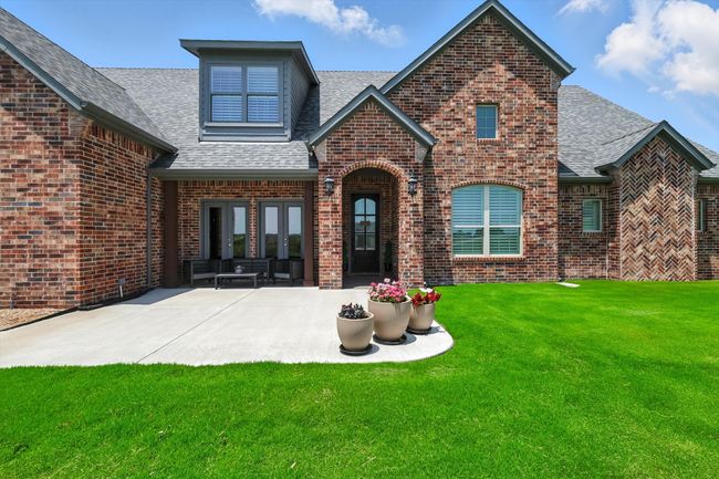 Back of property with brick siding, a shingled roof, a lawn, and a patio area | Image 4