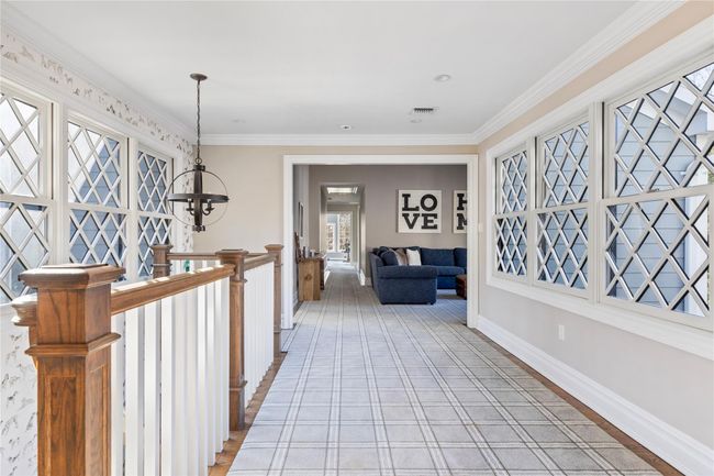 Hallway with visible vents, ornamental molding, baseboards, and a notable chandelier | Image 40
