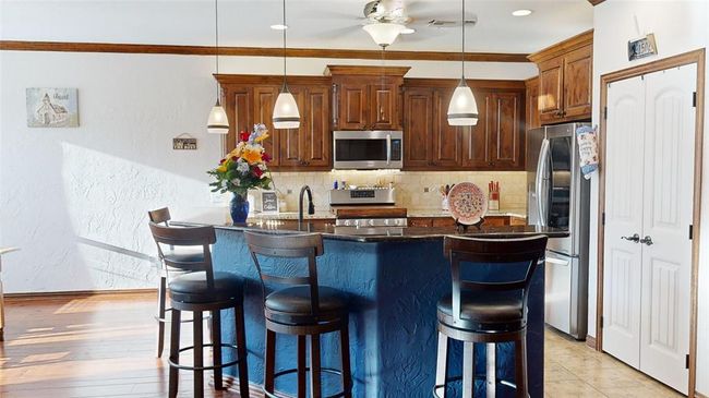 Kitchen featuring stainless steel appliances, a kitchen breakfast bar, backsplash, a ceiling fan, and pendant lighting | Image 17