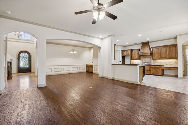 Unfurnished living room featuring ornamental molding, a chandelier, arched walkways, light wood-style floors, and a ceiling fan | Image 13