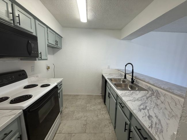 Kitchen with electric range, black microwave, a textured ceiling, and gray cabinetry | Image 9