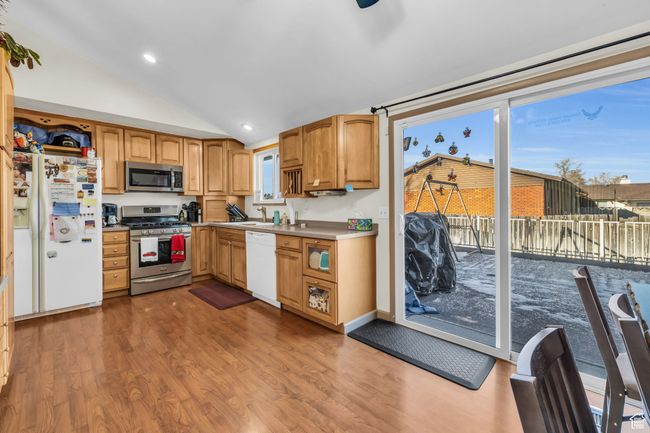 Kitchen with vaulted ceiling, recessed lighting, a sink, appliances with stainless steel finishes, and wood finished floors | Image 8