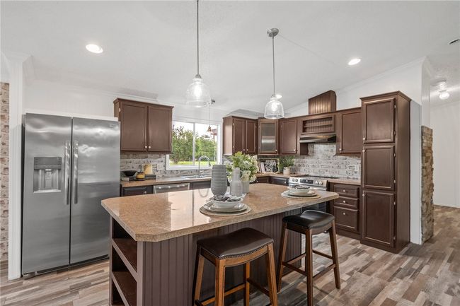 Kitchen featuring stainless steel appliances, open shelves, crown molding, backsplash, and dark brown cabinets | Image 5
