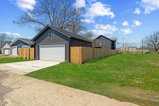 view of home's exterior featuring board and batten siding, a yard, a garage, and fence | Image 37