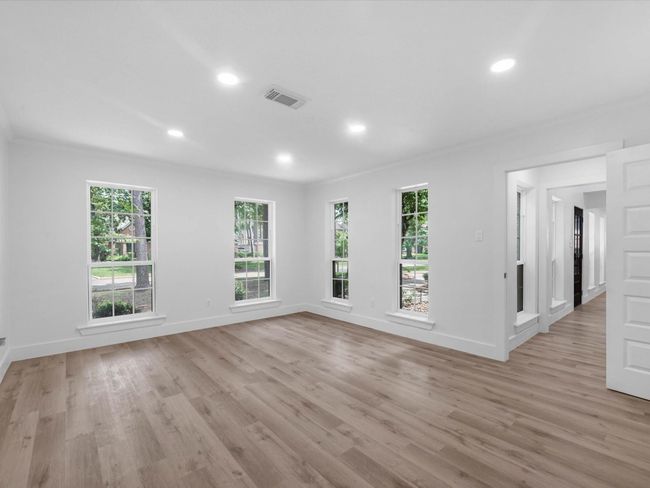 This photo shows a bright, spacious living area with large windows, light wood flooring, and recessed lighting, offering a modern and inviting atmosphere. | Image 20