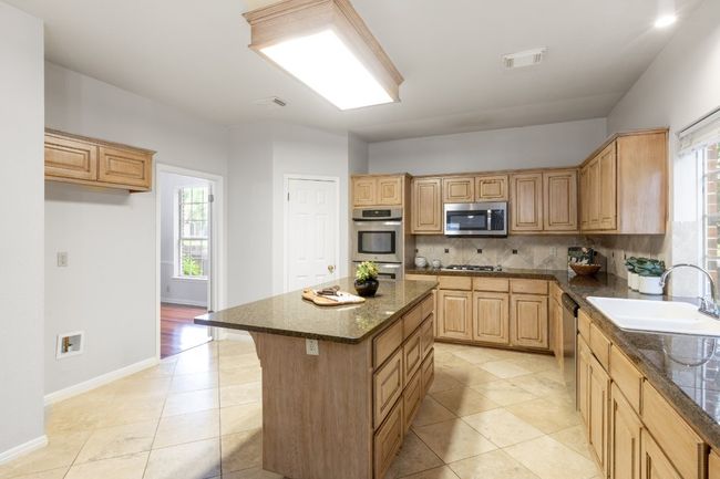 Kitchen featuring a sink, appliances with stainless steel finishes, light brown cabinetry, and tasteful backsplash | Image 17