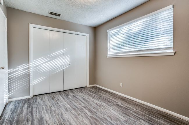 Unfurnished bedroom with a closet, baseboards, a textured ceiling, and wood finished floors | Image 14