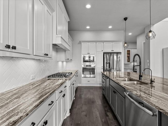 Chef's eat-in island kitchen features 42" cabinets with crown molding, under cabinet lighting, designer backsplash, stainless steel appliances and legthy countertops | Image 11